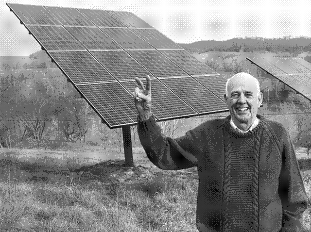 A photo of Berry from December 2011, smiling and holding up a peace sign in front of his solar panels. He is 77 in this photo.